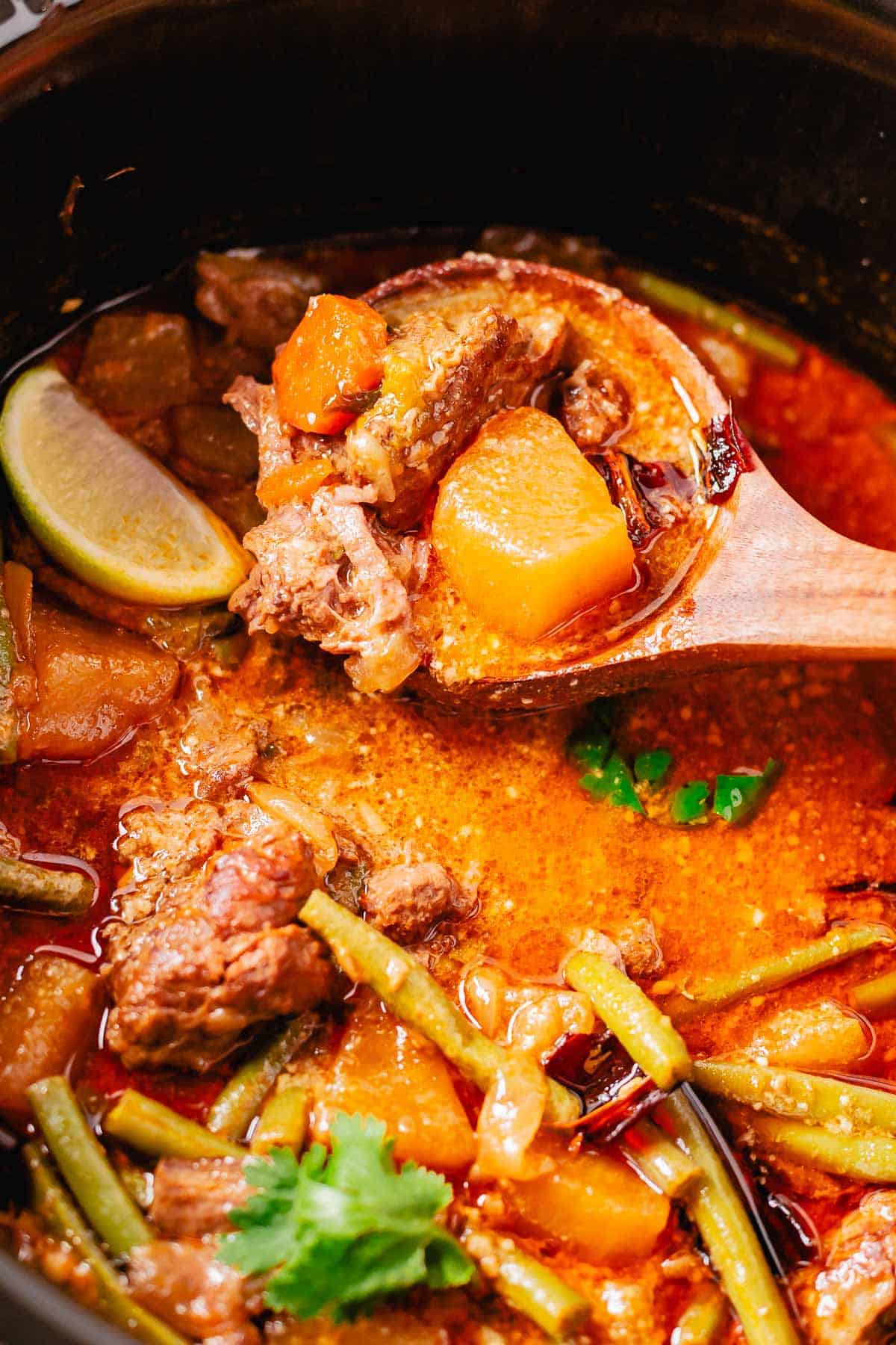 massaman beef curry on a wooden spoon close up shot