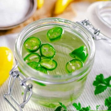 Spicy simple syrup in a small sealed glass container with fresh seeded jalapeno slices inside