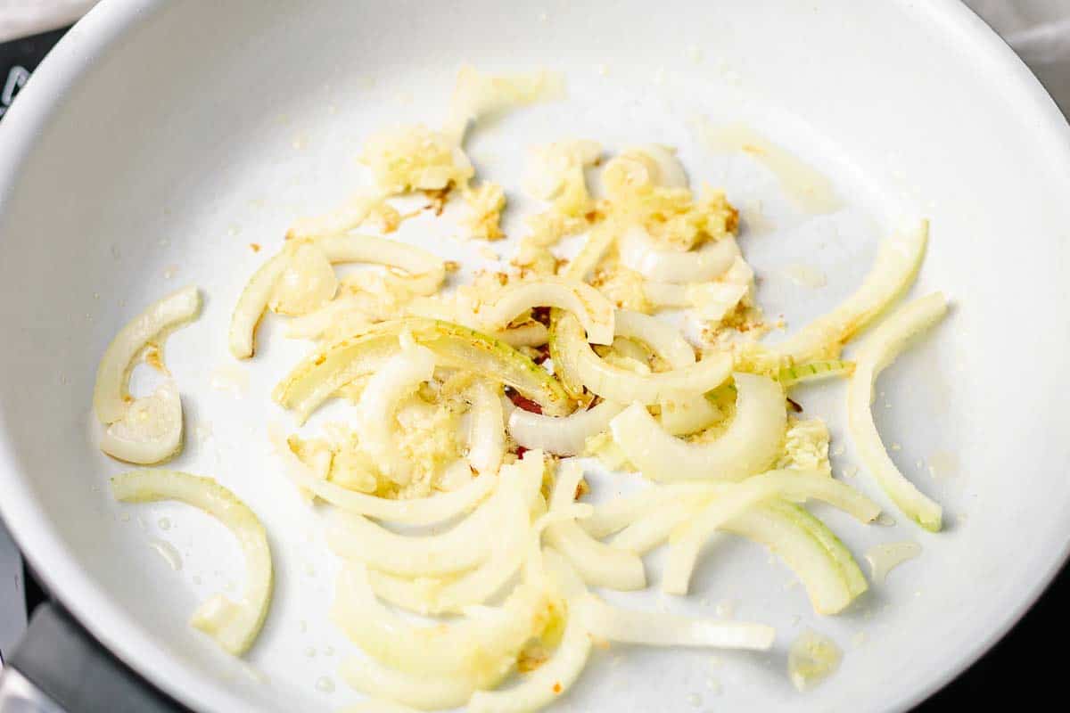 onion garlic and ginger stir fry in a white pan