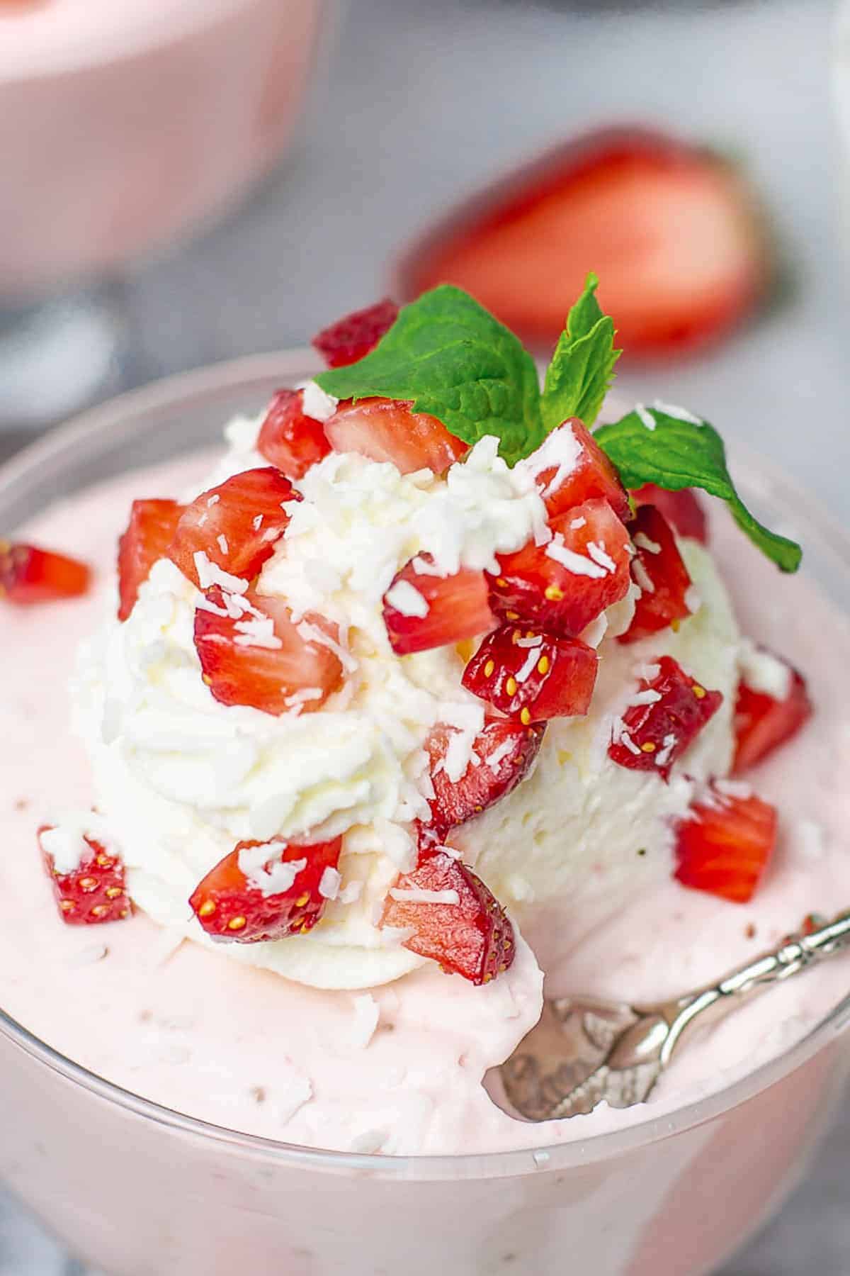 Strawberry Mousse in a glass cup with whipped cream and strawberries close up shot