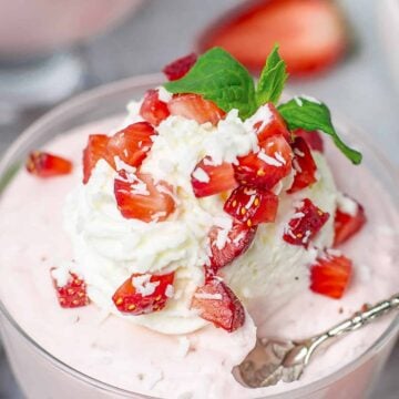 Strawberry Mousse in a glass cup with whipped cream and strawberries closeup shot