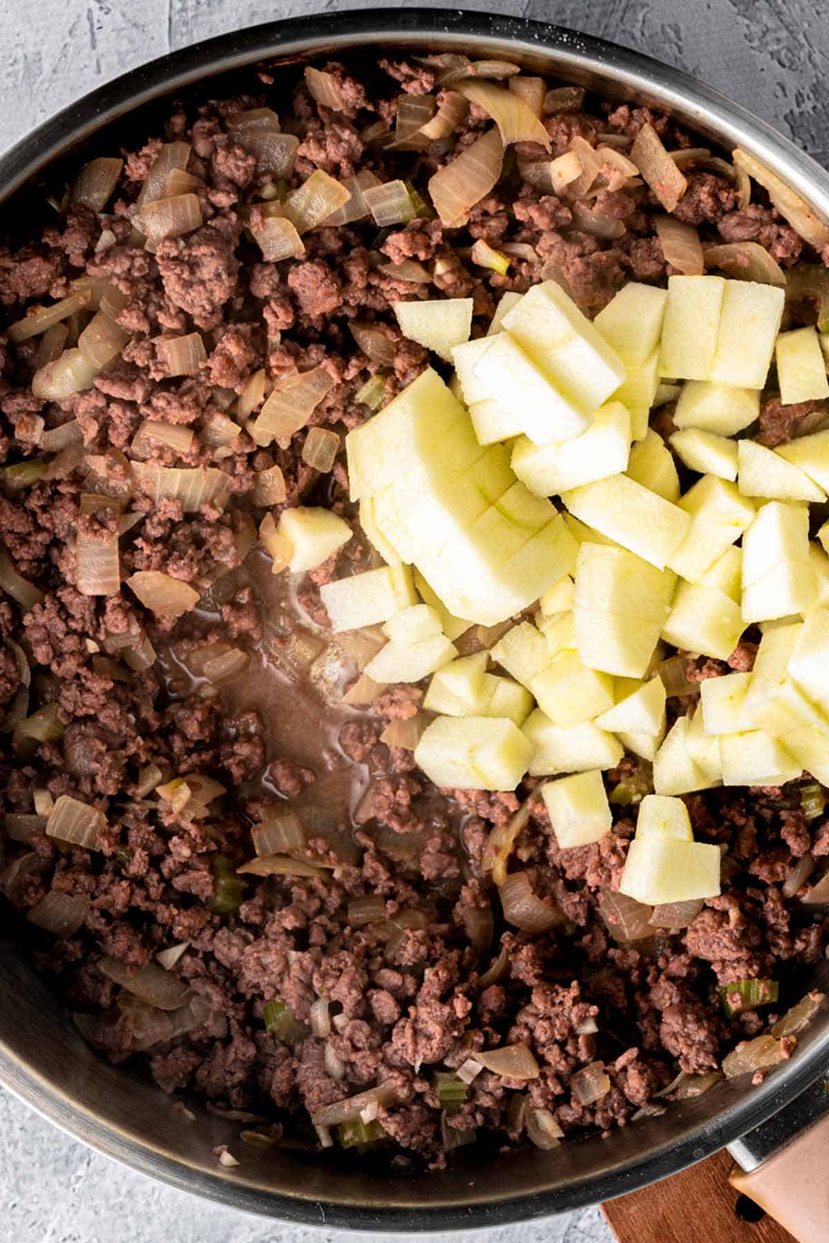 cooking beef and apples in skillet.