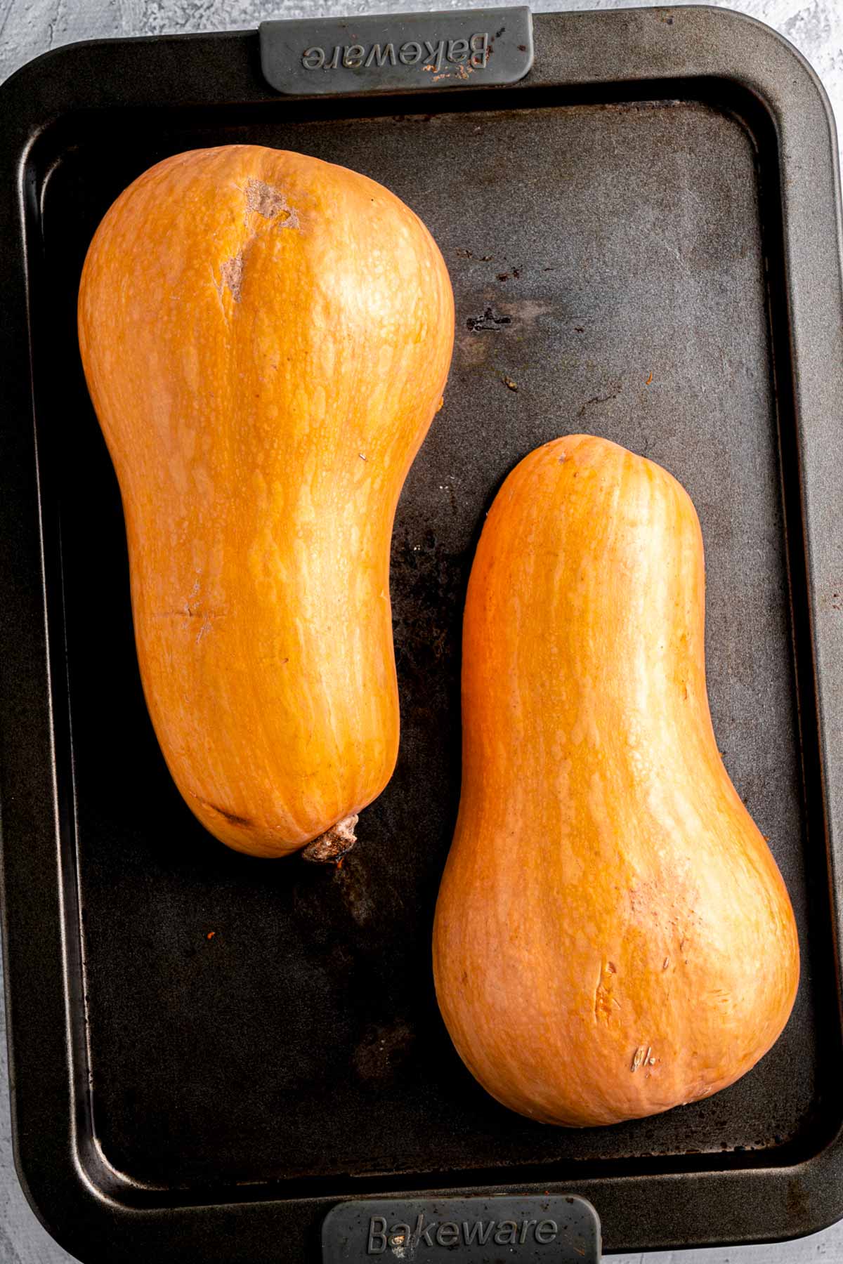 two butternut squash halves on baking sheet.