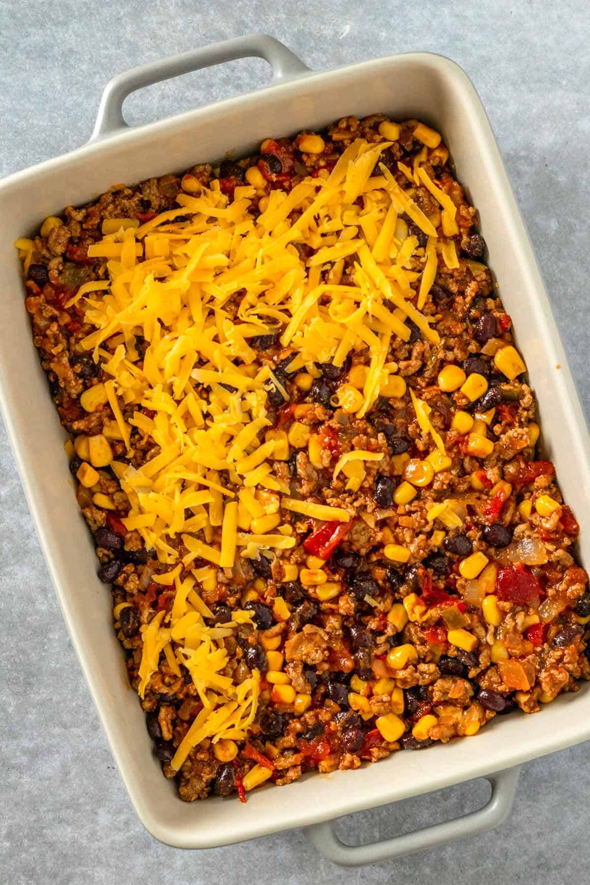 layered taco casserole in baking dish before baking