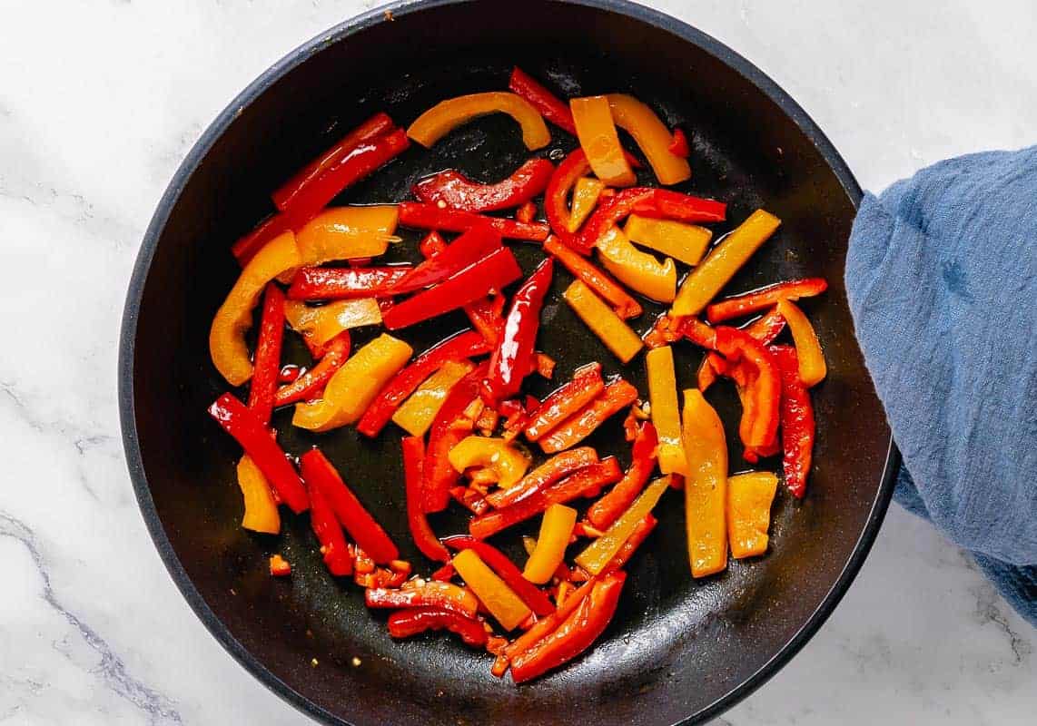 saute bell pepeprs and red hot chili peppers in a black skillet