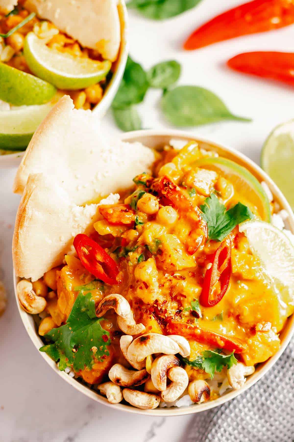 final image of pumpkin curry in a bowl with rice and pita bread with a marble background