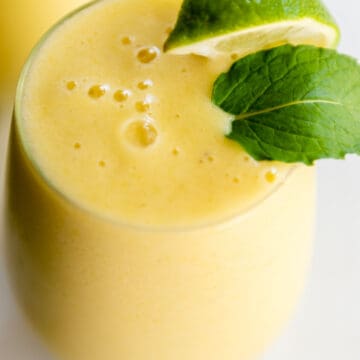 tropical smoothie in a tall glass with mint and lime wedge