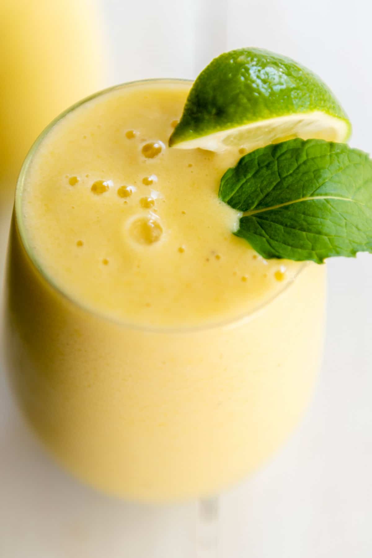 tropical smoothie in a tall glass with mint and lime wedge