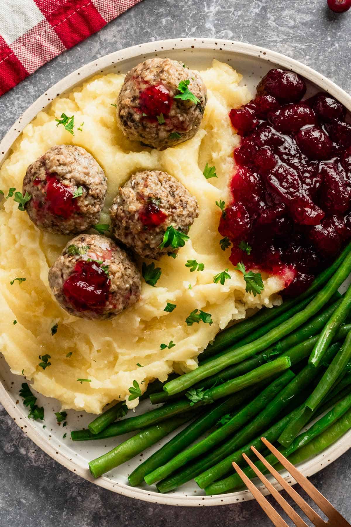 turkey stuffing meatballs served with cranberry sauce, mashed potatoes and green beans.