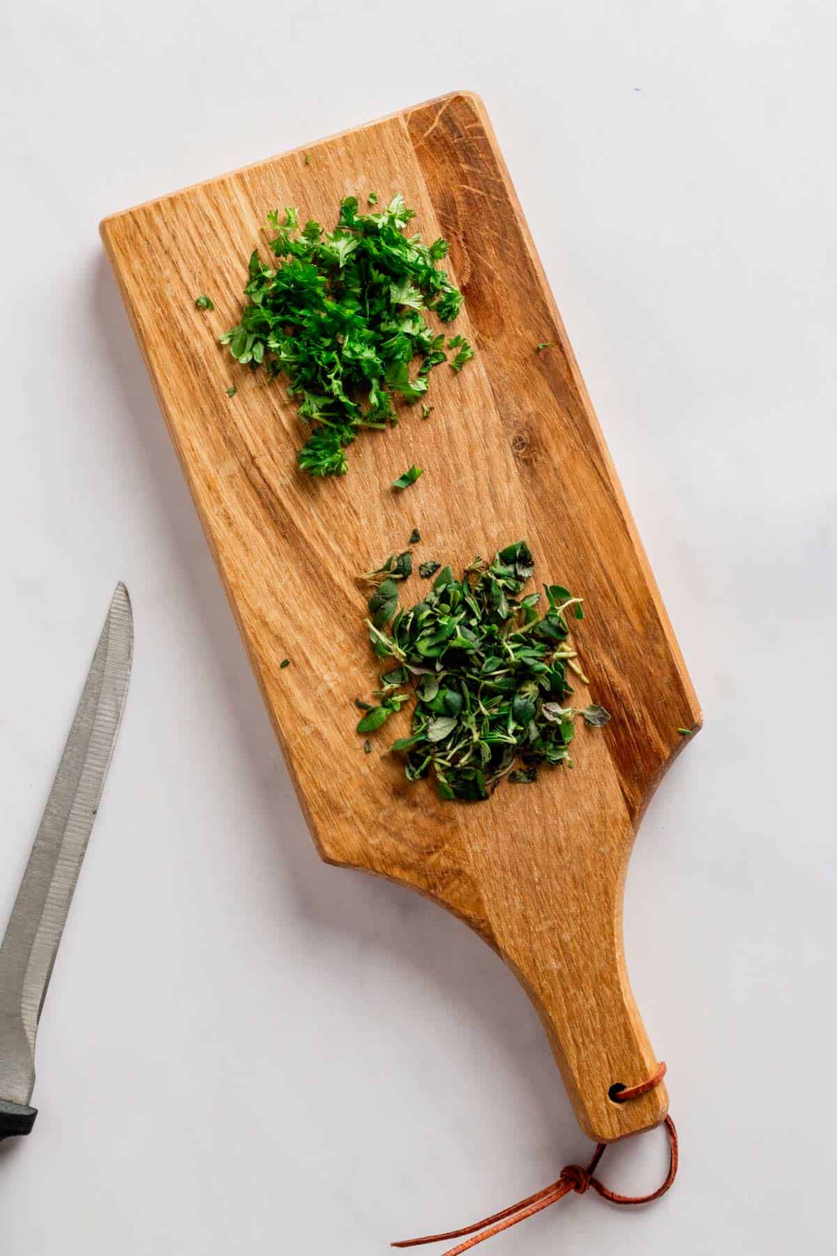 herbs on wooden cutting board.