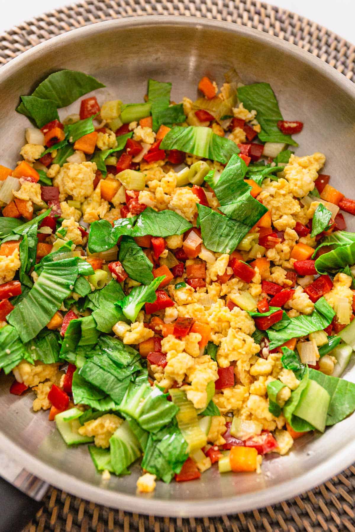 scrambled eggs and vegetables cooking in skillet for egg fried rice