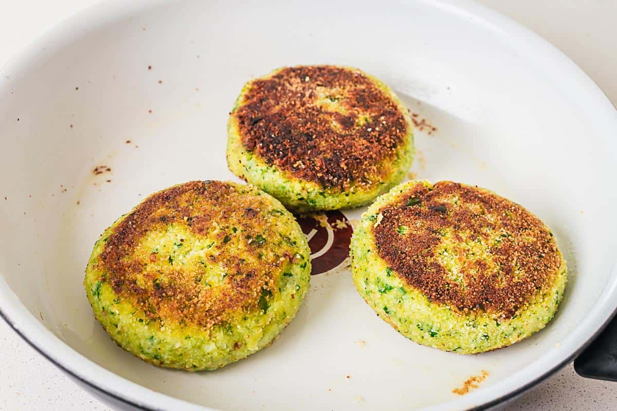 vegetarian patties frying in a white skillet