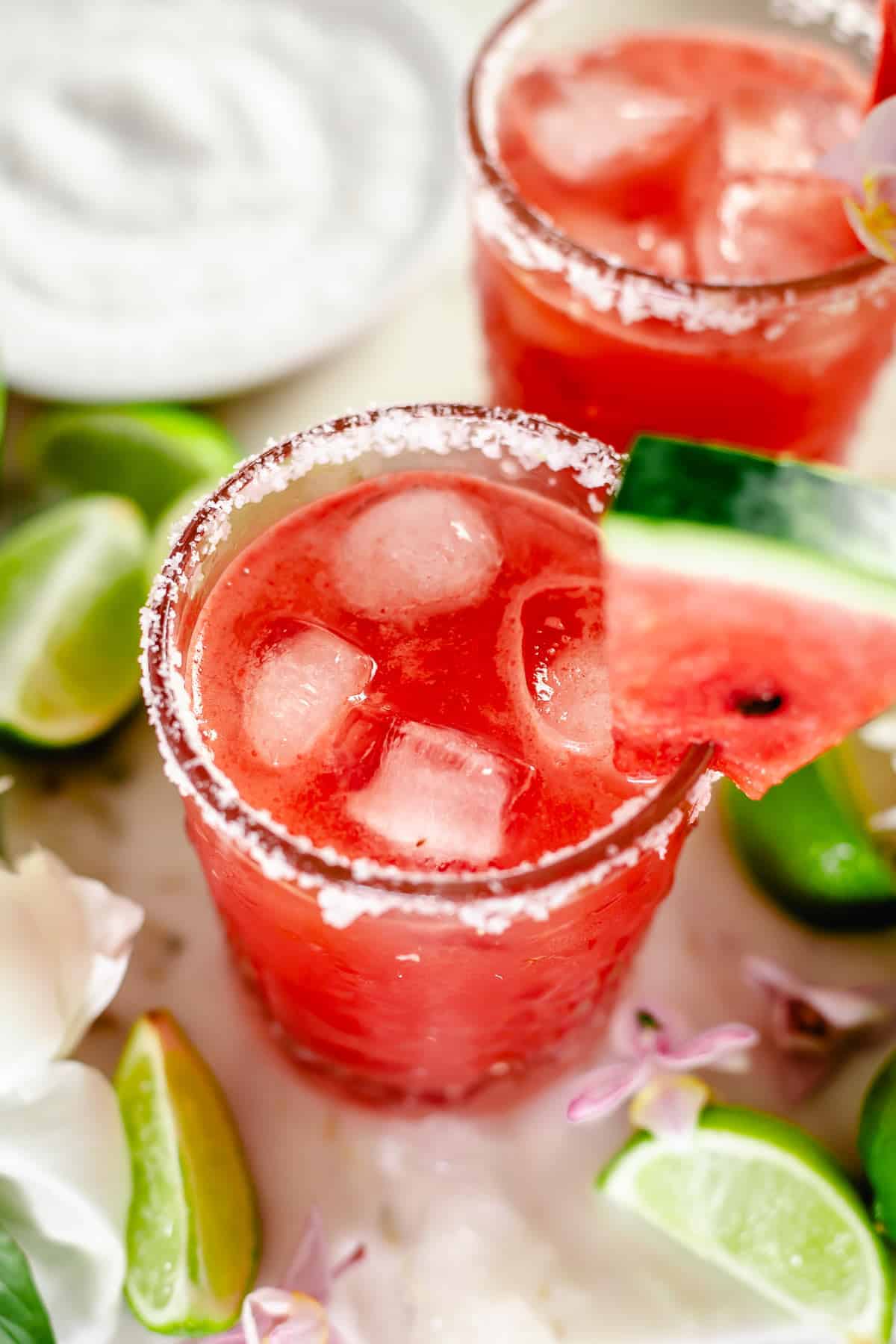 angle view shot of watermelon margarita in whisky glass with salt rim, watermelon slice